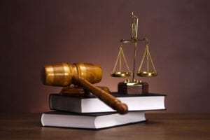 An image of a gavel, the scales of justice, and two large books.