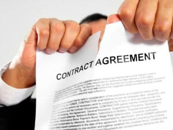 A breach of contract lawyer tearing up a contract agreement.